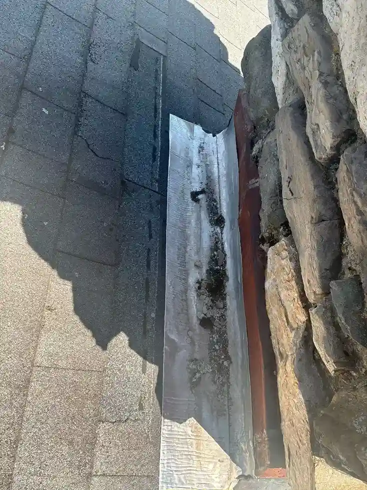 Metal flashing in the valley behind a stone chimney