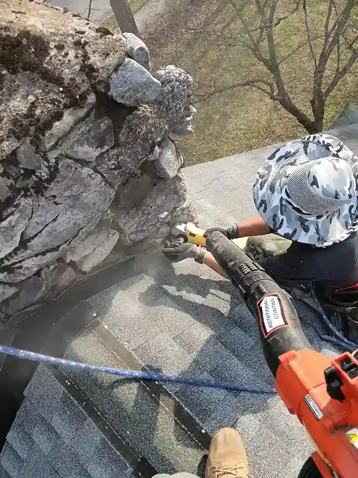 Roofer cutting groove into stone chimney for flashing