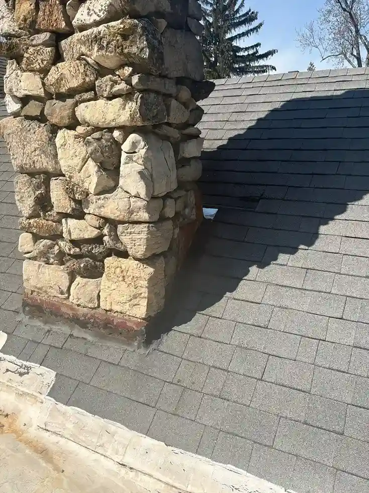 Stone chimney flashing installation on asphalt shingles